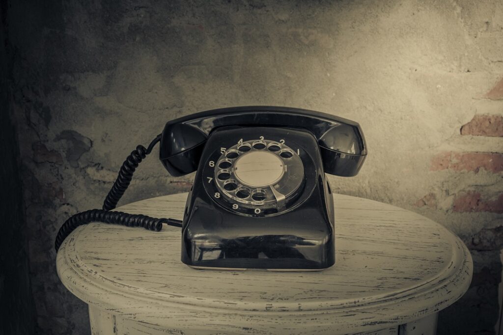 Vintage black phone on old walls background