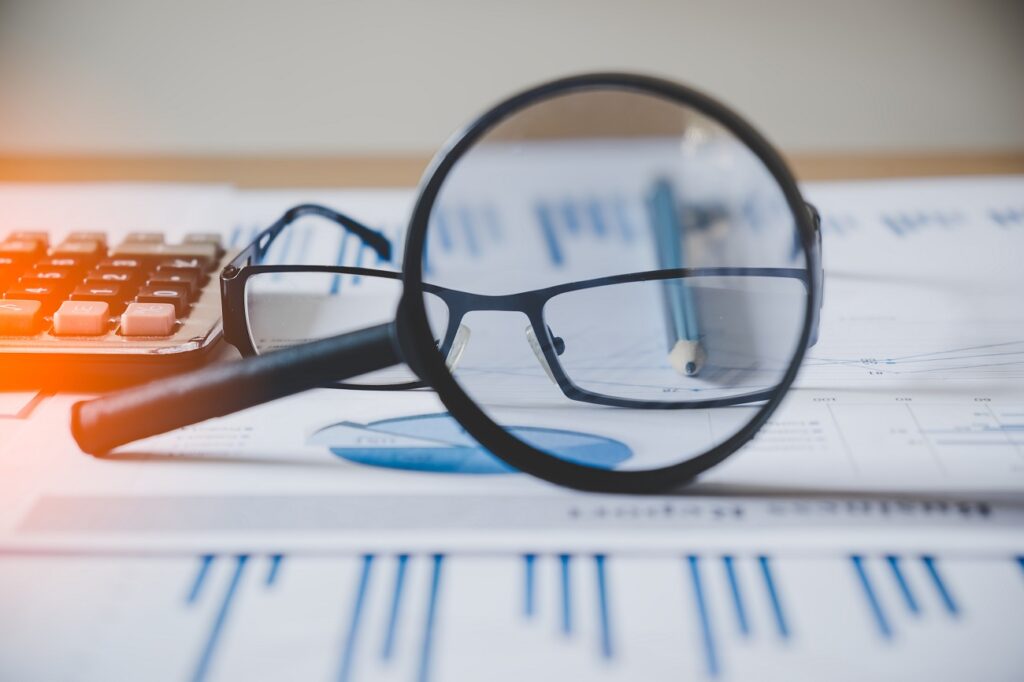 charts and graphs with magnifying glass and pencil, calculator,