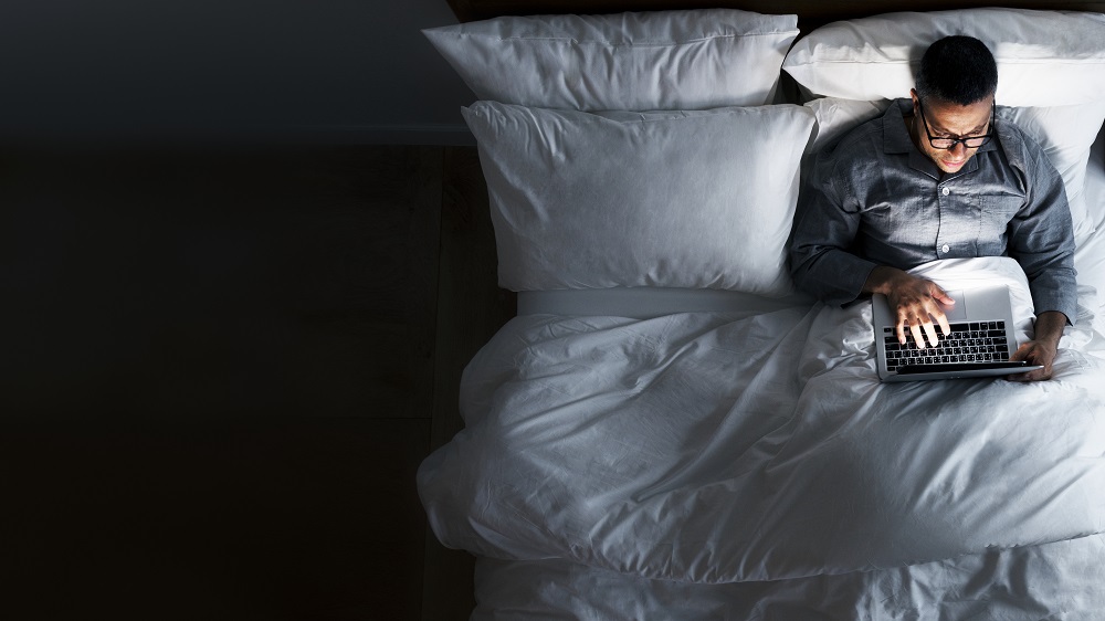 Man using a laptop in the bed