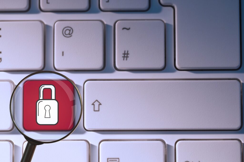 composite of padlock symbol on keyboard with magnifying glass